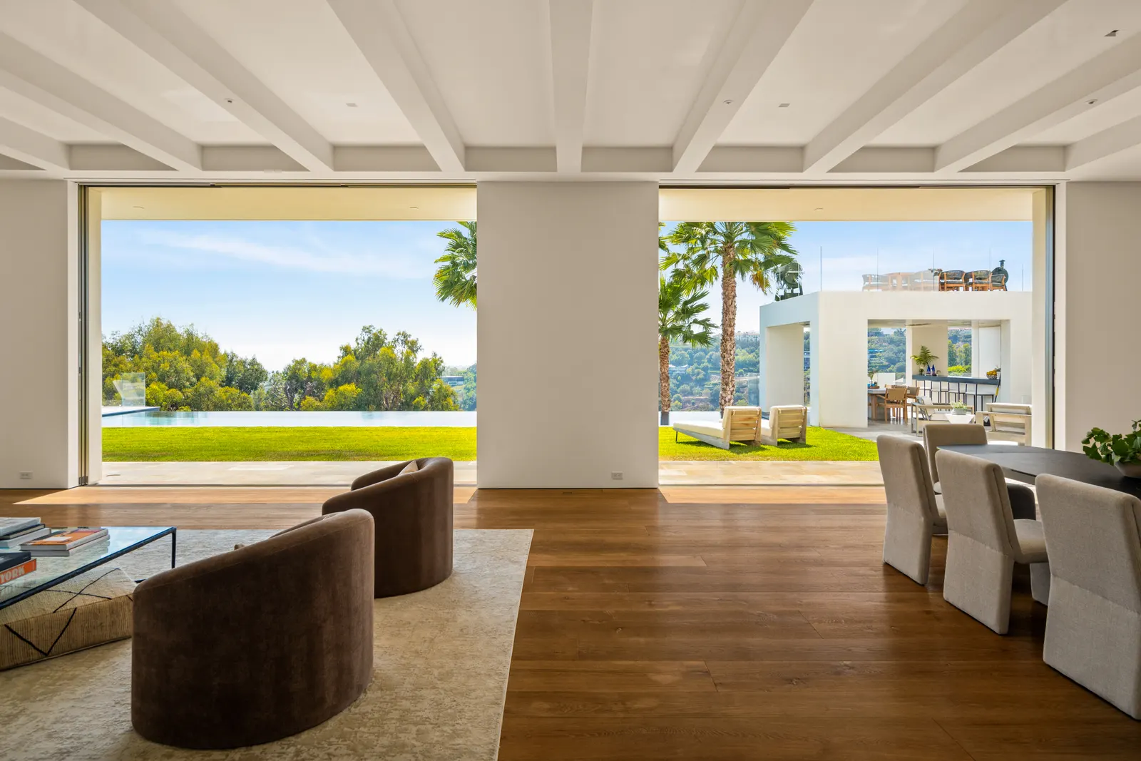 Great room at Stradella Residence with glass walls pocketed open to the lawn, pool and canyon beyond