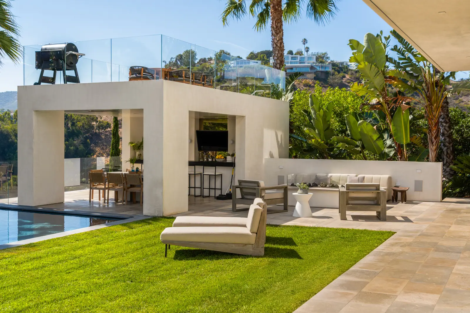 Open-air pavilion with dining and lounge seating beside the pool