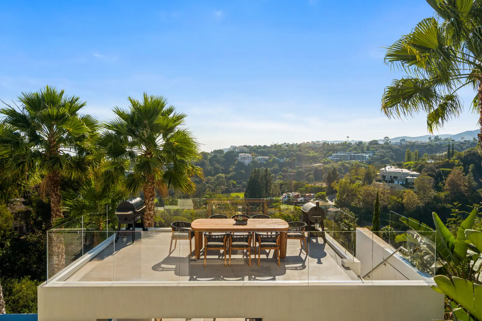Roof terrace dining table above the canyon with palms alongside
